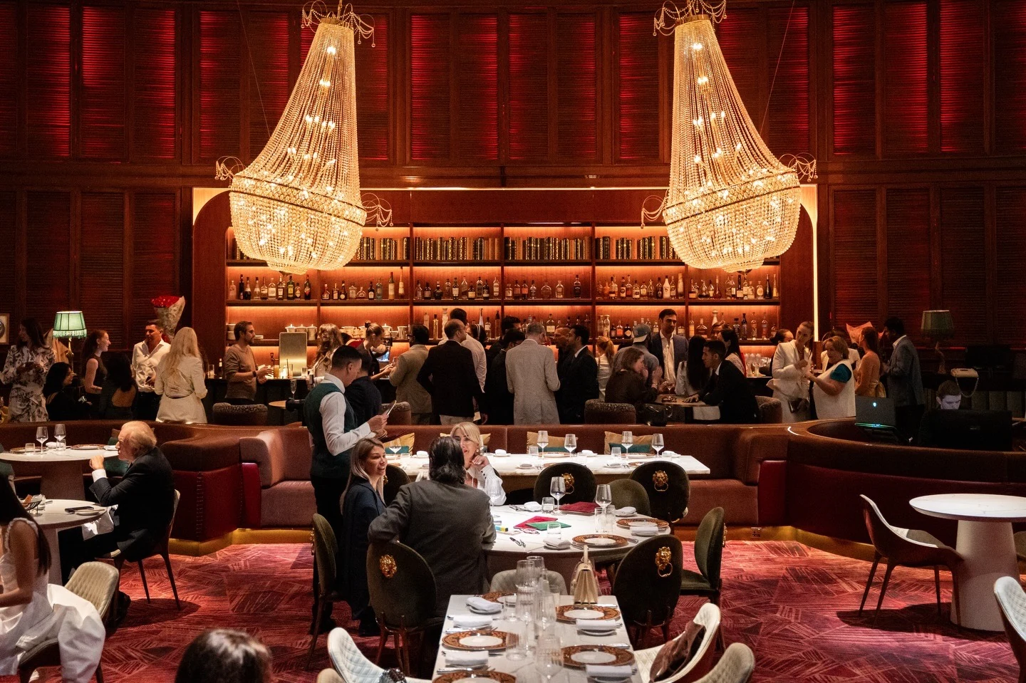 Belcanto's main dining room full of guests beneath two crystal chandeliers